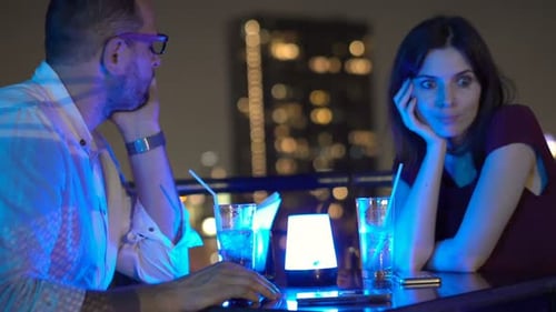 Bored, Offended Couple Sitting on Terrace in Bar and Drinking Beverage At