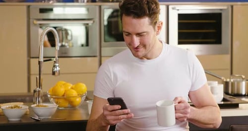 Man With Coffee And Phone in Modern Kitchen