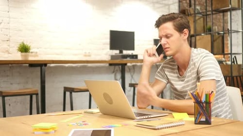 Young Man Talking on Phone in Office