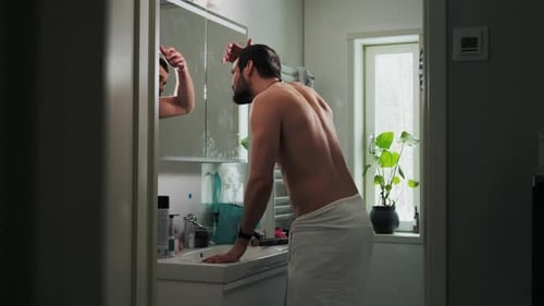 Man looking in the mirror checking thinning hairline