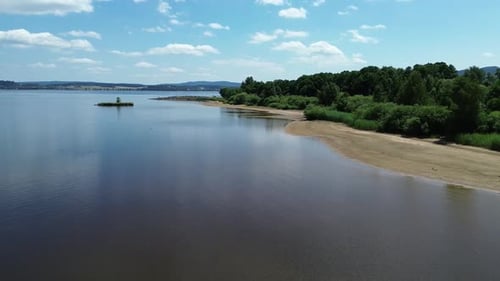 cinematic view from a drone flying over a sandy beach on the shore of a big blue lake