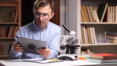 Scientist Using Microscope and Reading Tablet in Laboratory