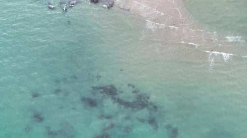 Aerial drone footage of sea ocean waves reaching shore. Beach with aerial drone. Beach and street.