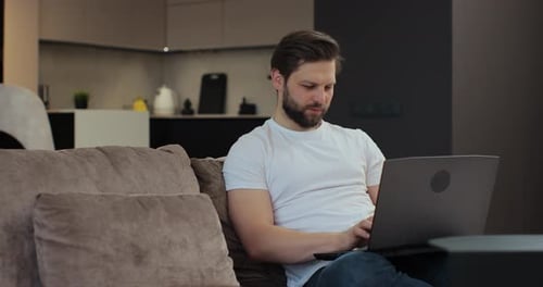 Young Adult Man Using Laptop on Couch