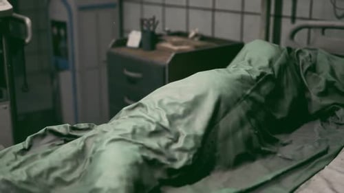 Hospital Bed with a Patient Covered in a Green Blanket During Evening Hours