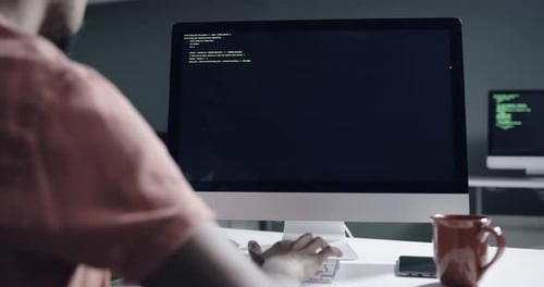 4k video footage of a young male programmer working on a desktop computer late at night
