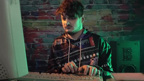 Young Adult Typing at Computer in Dark Room