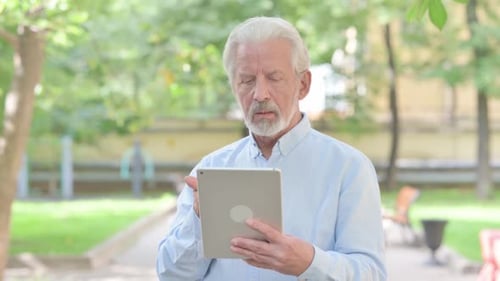 Senior Man Video Calling on Tablet in Park