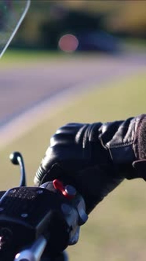 Hand on motorcycle throttle in country road setting