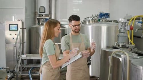 Homme et femme travaillant dans une brasserie artisanale vérifiant le pH de la bière.