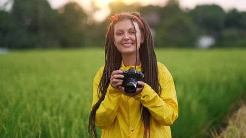 Photographer Wearing Yellow Raincoat Taking Pictures in Green Field at Sunset