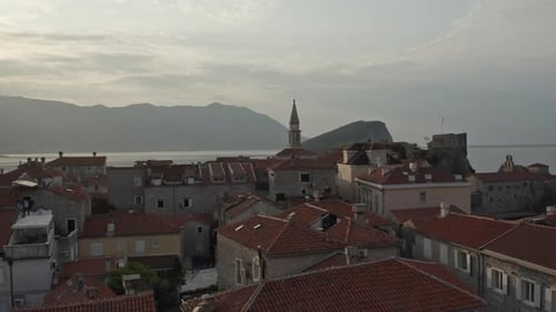 Morning drone shot in old town Budva, Montenegro with ocean and island in background.