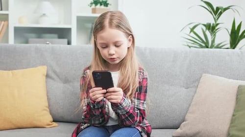 Girl Using Smartphone Sitting on Sofa at Home