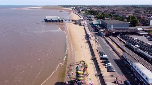 Aerial view above Grimsby Cleethorpes seaside fairground along coastline to holiday pier tourist att