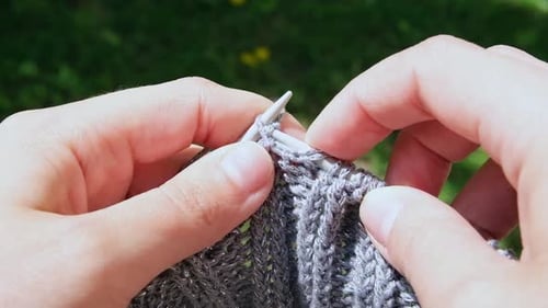 Close Up of a Woman Knits Wool Creating a Warm Gray Handmade Sweater with Her Hands and Sewing