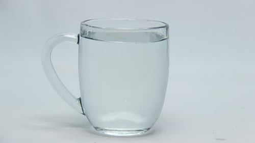 Red Liquid Drops into Water in Glass Mug