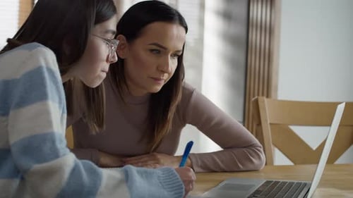 Mother Helps Teenage Girl With Homework at Home