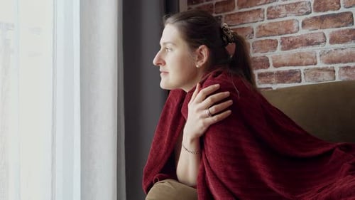 Woman Wrapped in Blanket Sitting by Window