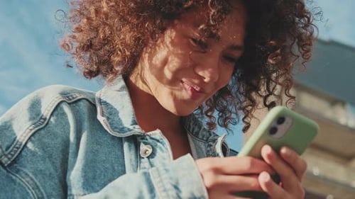 Smiling Woman Using Mobile Phone in City