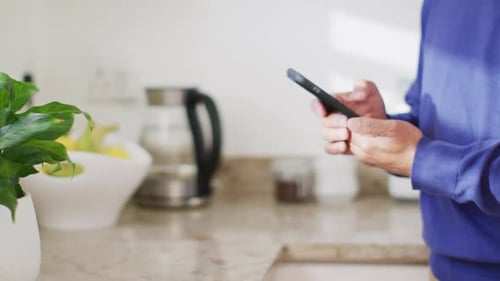 Hands Using Phone in Bright Kitchen Environment