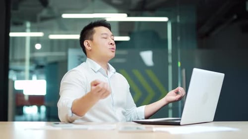 Asian business man meditating. Successful businessman meditates sitting at table in modern office,