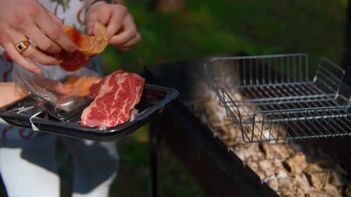 Man cooks two pieces of beef or pork on grill