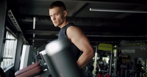 Focused Young Man Using Gym Equipment for Fitness Training