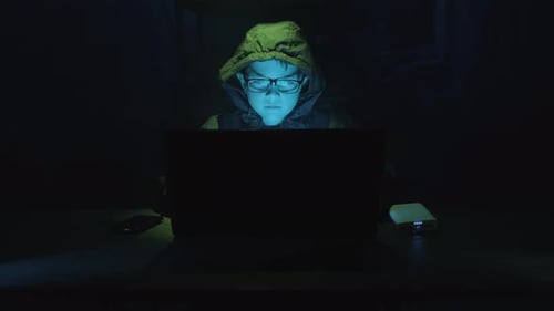 Young Boy Hacker In A Hoodie Exploiting Weaknesses In A Computer System. - close up