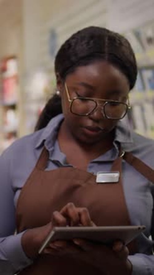 Black Female Sales Assistant with Tablet Checking Stocks of Beauty Products