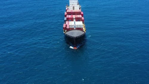 Aerial footage of a container ship approaching a commercial port.