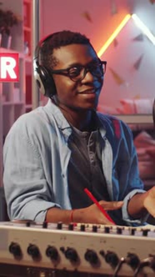 Black Blogger in Headphones Recording Podcast Interview in Audio Studio