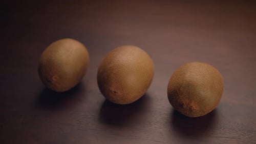 Drei reife Kiwifrüchte, die auf einer rustikalen Holzoberfläche angeordnet sind und ihre lebendige Farbe zur Geltung bringen