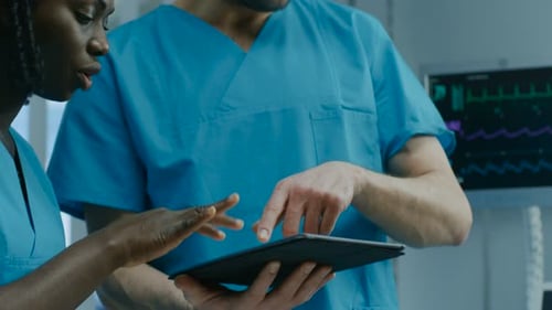 In the Hospital Male and Female Nurses Use Tablet Computer while Talking. Professional Medical Staf