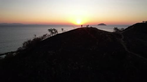 Coastal Hilltop Sunset View with Silhouetted Figures