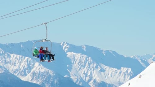 Group Of Skiers Sit In Ski Lift With Mountains Views