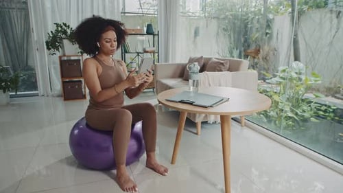 Woman Uses Tablet While Sitting on Exercise Ball