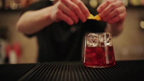 Nahaufnahme von Händen, die frische Zitrone mit Eis in ein Cocktailglas drücken