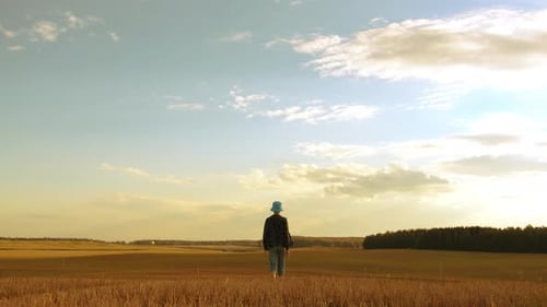 Teen Boy Walks on a Field in Sunny Weather in the Evening Walk Against the Backdrop of Beautiful