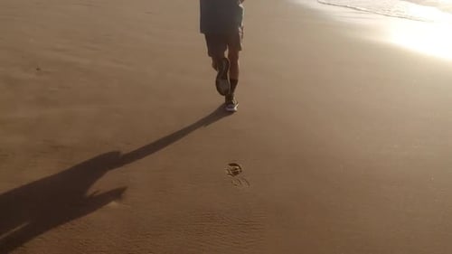 Faites du jogging au lever du soleil sur la plage, seuls les pieds et les jambes sont visibles