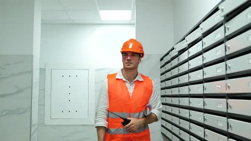 Construction Worker Inspecting Mailboxes in Urban Building