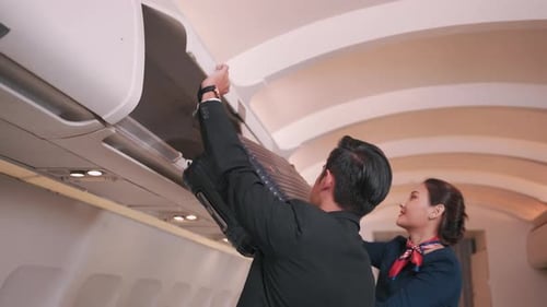 Un homme d'affaires asiatique met une valise dans un compartiment à bagages