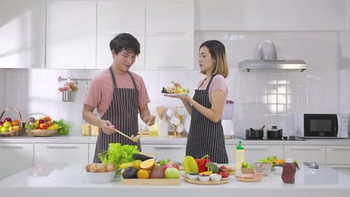 Young Couple Laughing and Cooking Salad Together