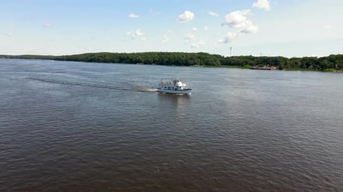 Small Cruise Ship sailing down a calm river, lovely sunny day. Drone shot.