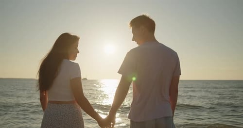 Couple s'embrassant au coucher du soleil debout ensemble sur la plage