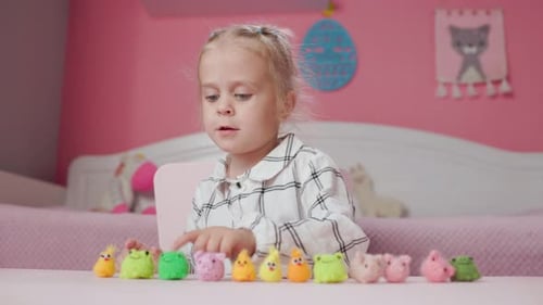 Mädchen spielt mit kleinen gestrickten Tierspielzeugen in einem Zimmer zu Hause