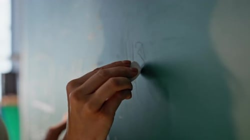 Young Adult Woman Writes on Chalkboard