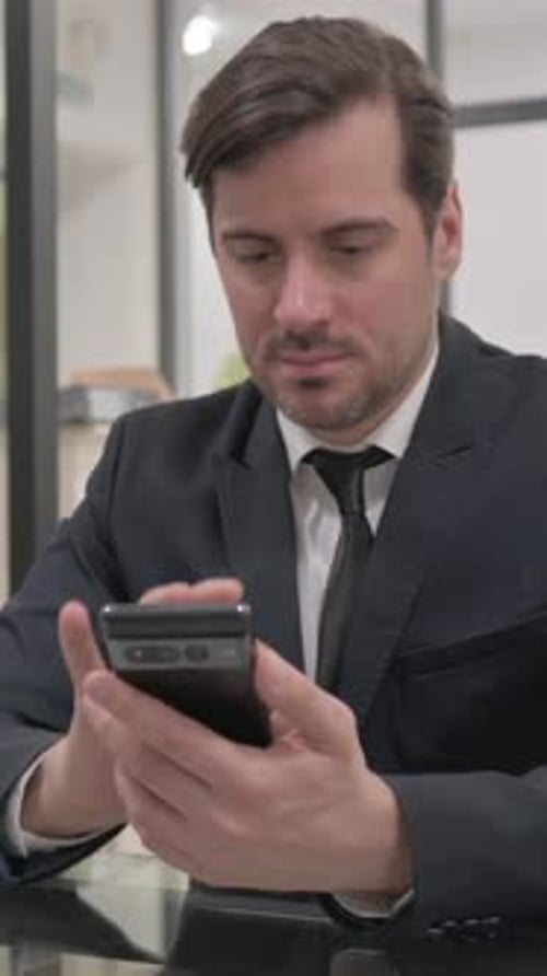Businessman Using Smart Phone Indoors in Office Setting