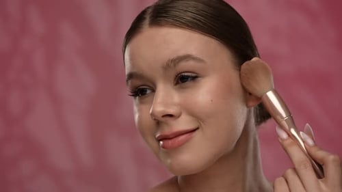 Young Woman with Makeup Posing at Camera in Studio Playfully Smiling Touching Applying Blushes with