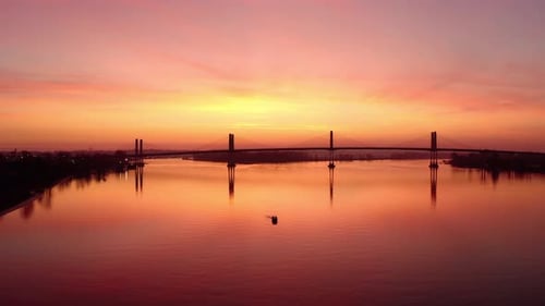 Aerial view of Boat in the middle of a River silhouetted by majestic Sunset