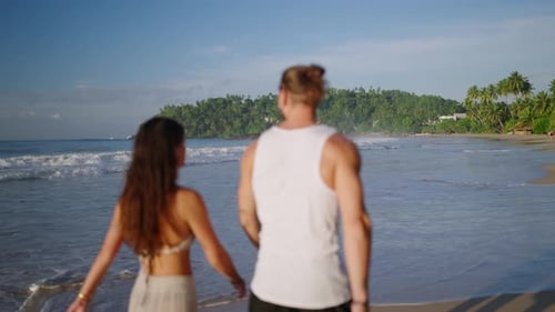 Young Biracial Happy Couple Unfocused Walking on the Beach Together Enjoying Summer Backview Shot